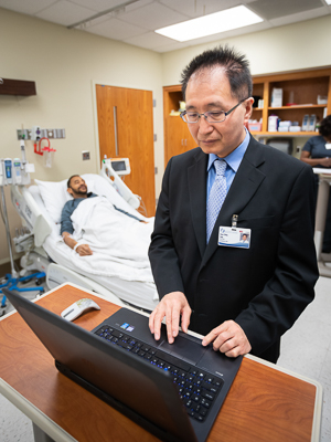 Doctor on computer with patient in the background